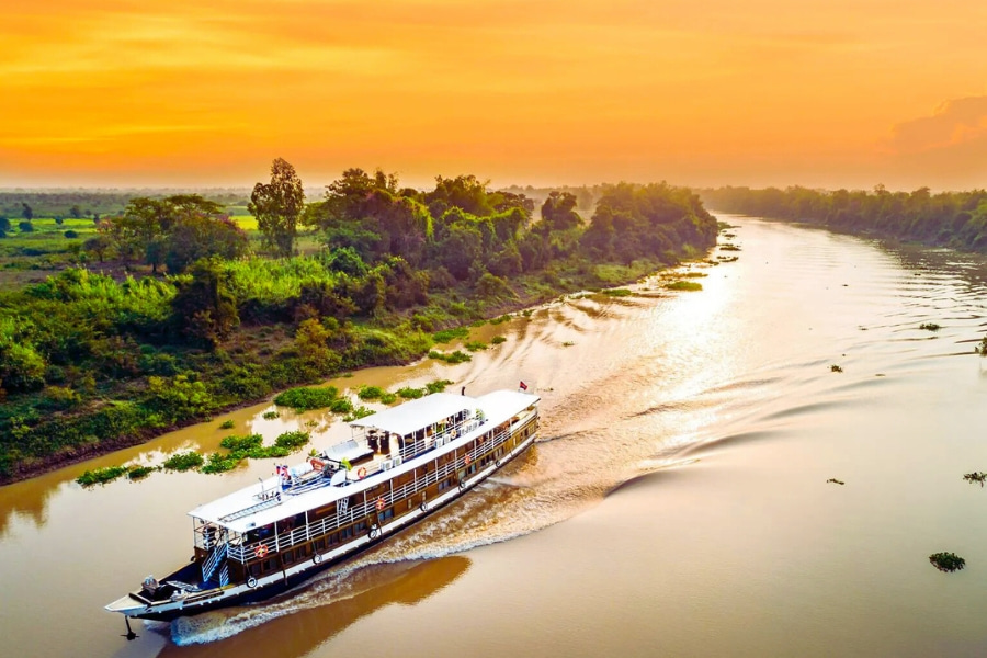 Mekong Delta river cruise sailing at sunset through lush green riverside scenery